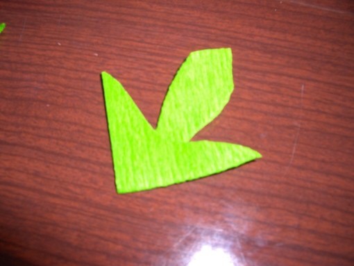 Kvadrat zelenega krep papirja dvakrat prepognemo, zatem pa iz njega izrežemo prikazano obl