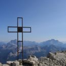 Križ na vrhu Tofane di Mezzo; visoki gori v ozadju sta Pelmo (3168 m; tik levo ob križu) t